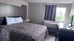 Un dormitorio con cama, escritorio, ventana con cortinas y radiador.