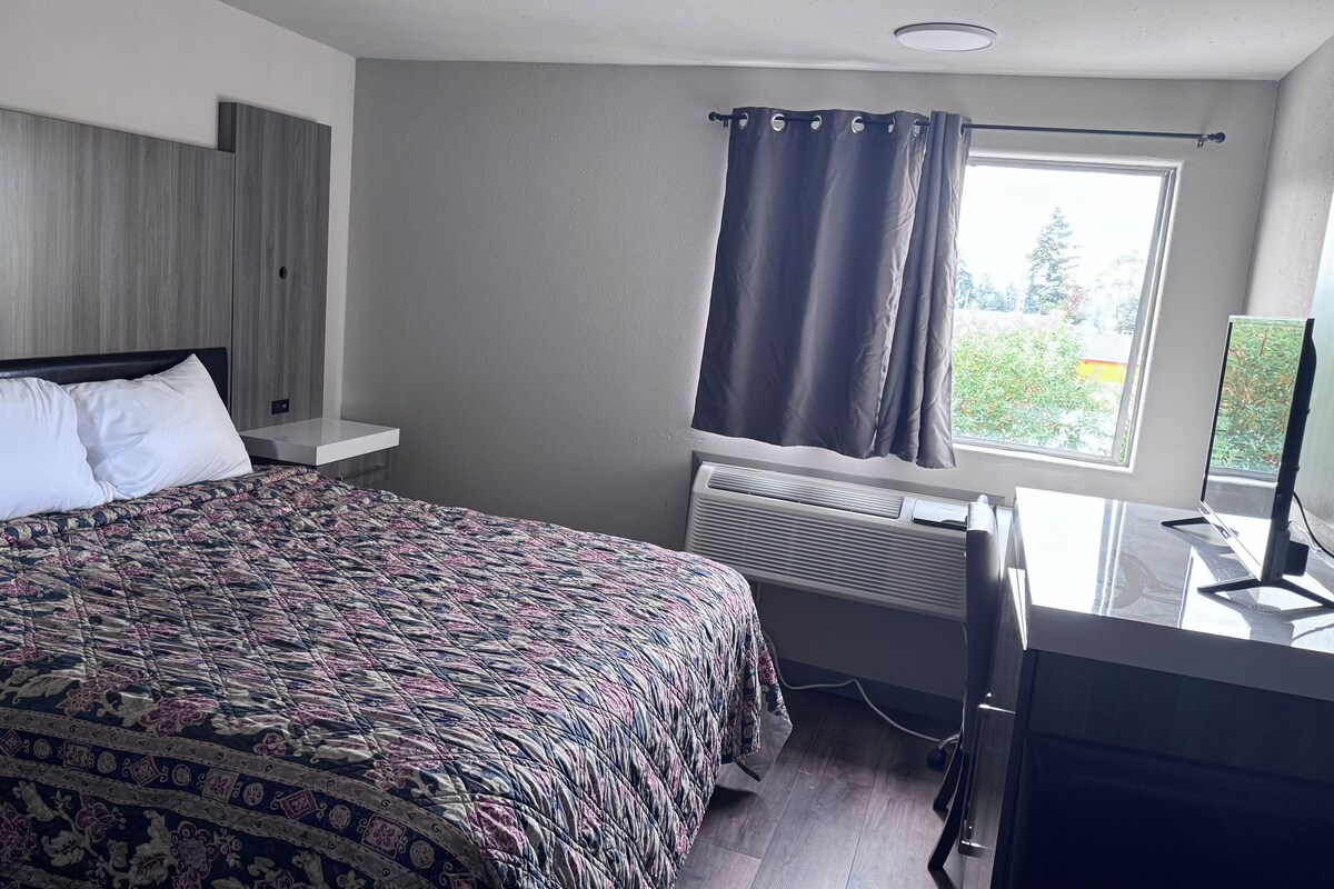 Ein Schlafzimmer mit einem Bett, einem Schreibtisch, einem Fenster mit Vorhängen und einer Heizung.
