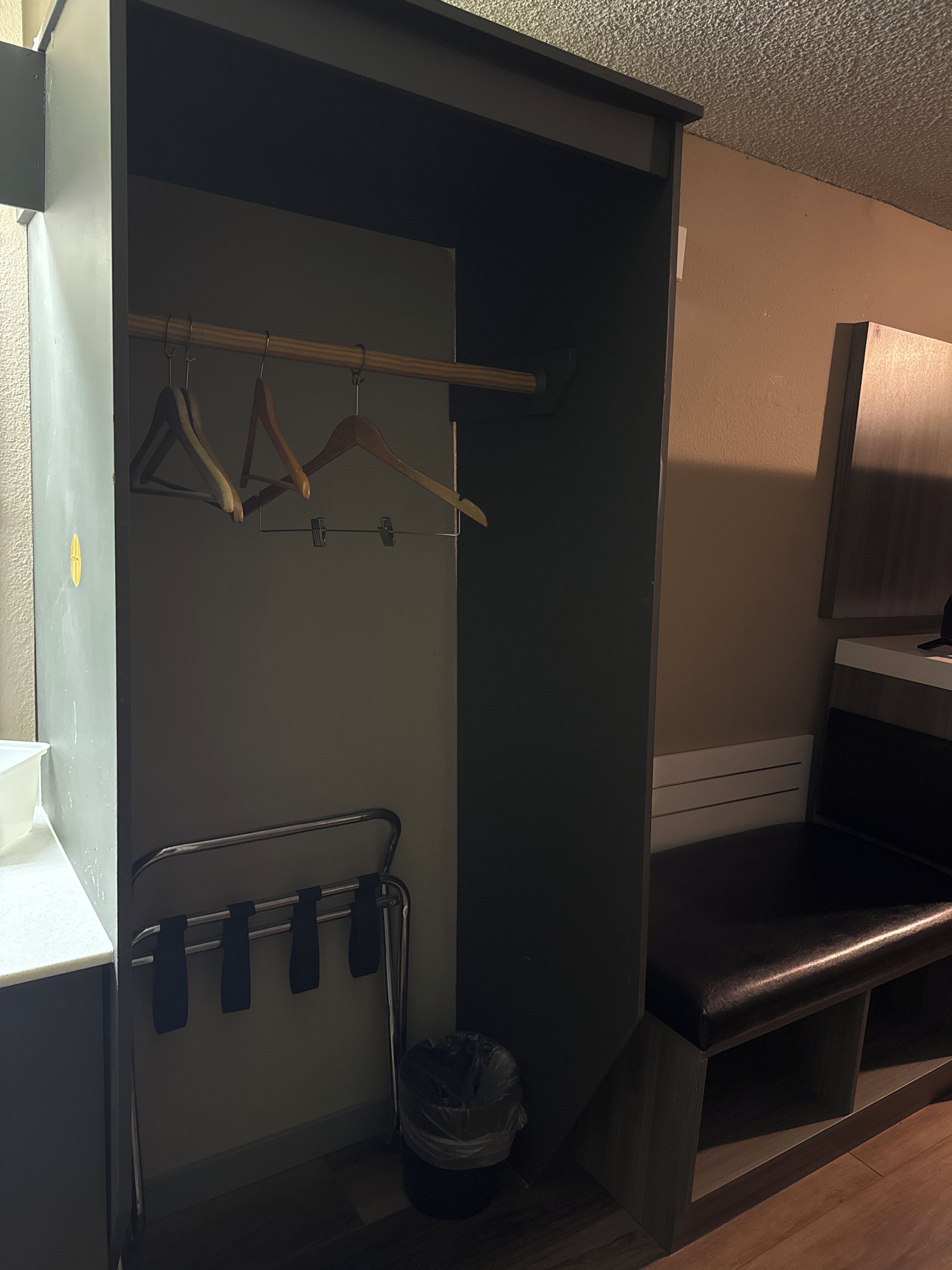 Een kleine badkamer met een douche, een handdoekhouder en een prullenbak.