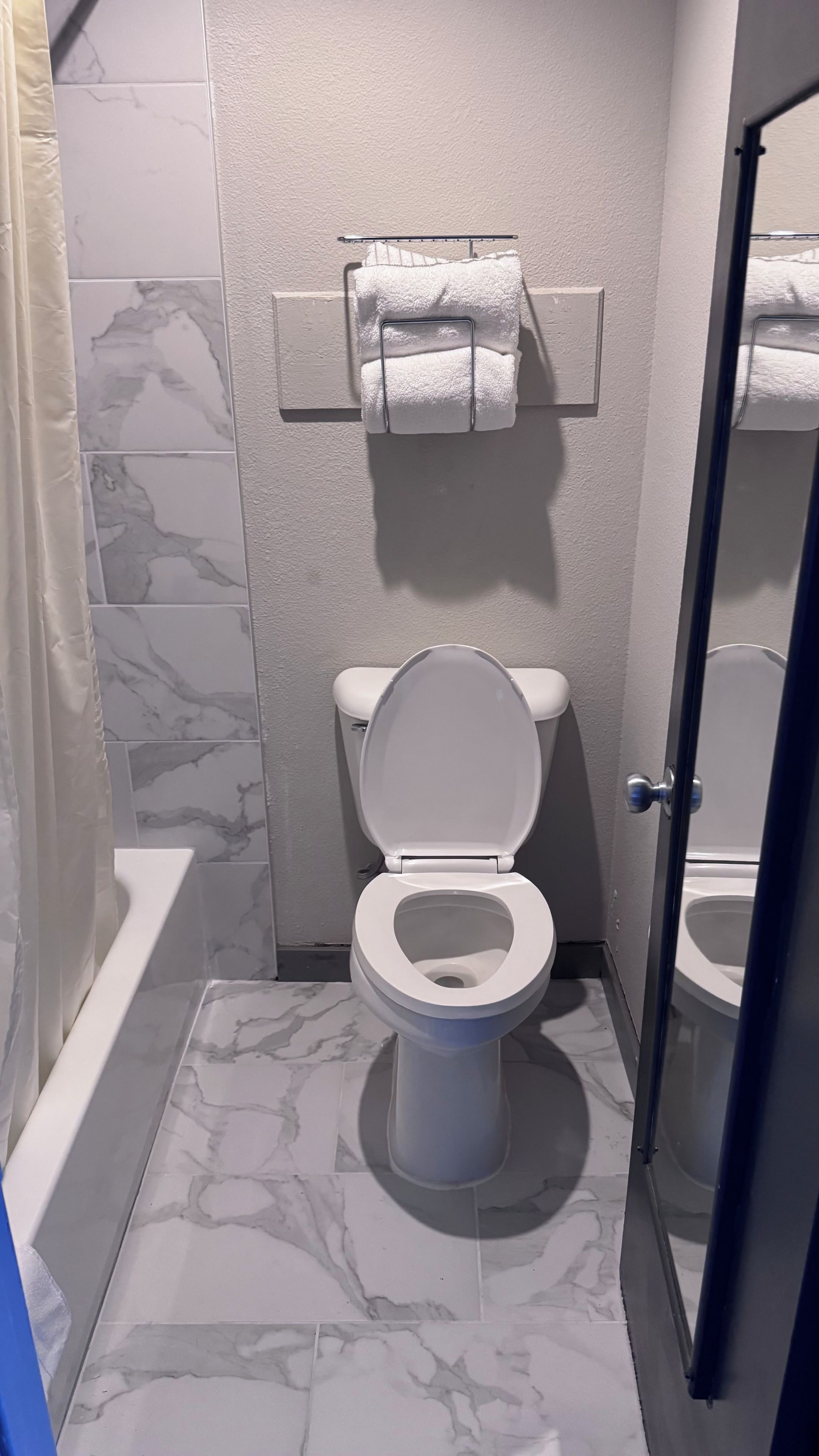 A bathroom with a toilet, a towel rack, and a bathtub.