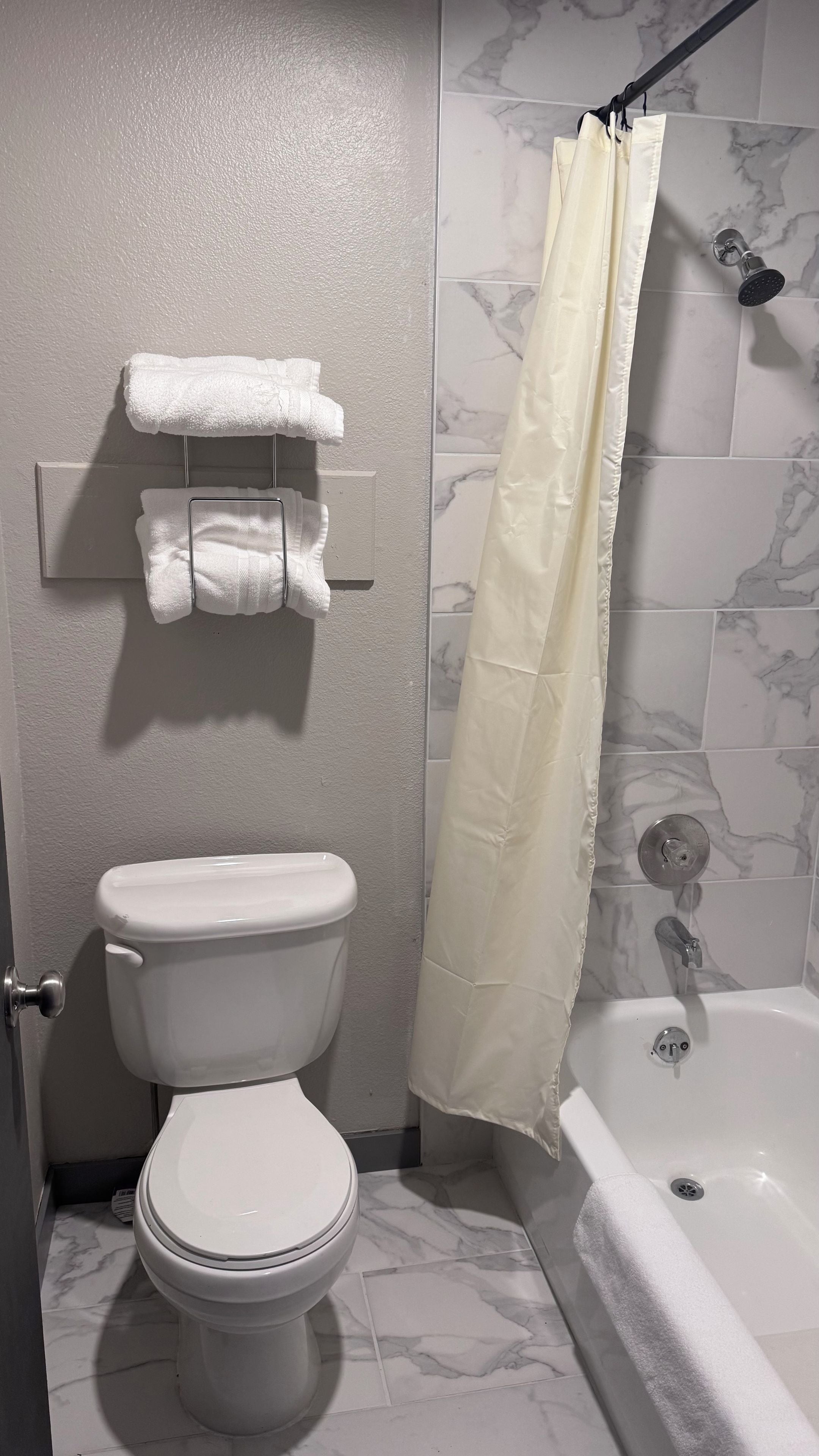 A bathroom with a toilet, a shower curtain, and a bathtub.