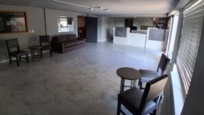 Un salón amplio con sofá, sillas, una mesita y una cocina al fondo.