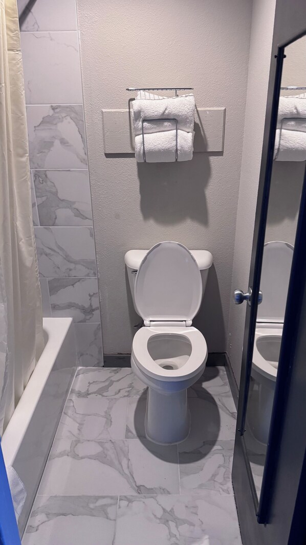 Ein Badezimmer mit Toilette, Handtuchhalter und Duschbereich.