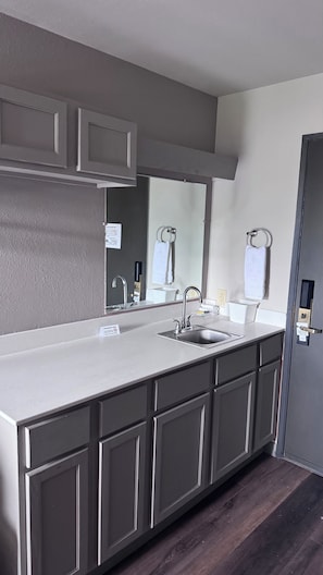 A modern bathroom with a large vanity, a sink, and a mirror. - Midway Inn (Bremerton)