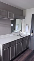 Un baño moderno con un tocador amplio, un lavamanos y un espejo.