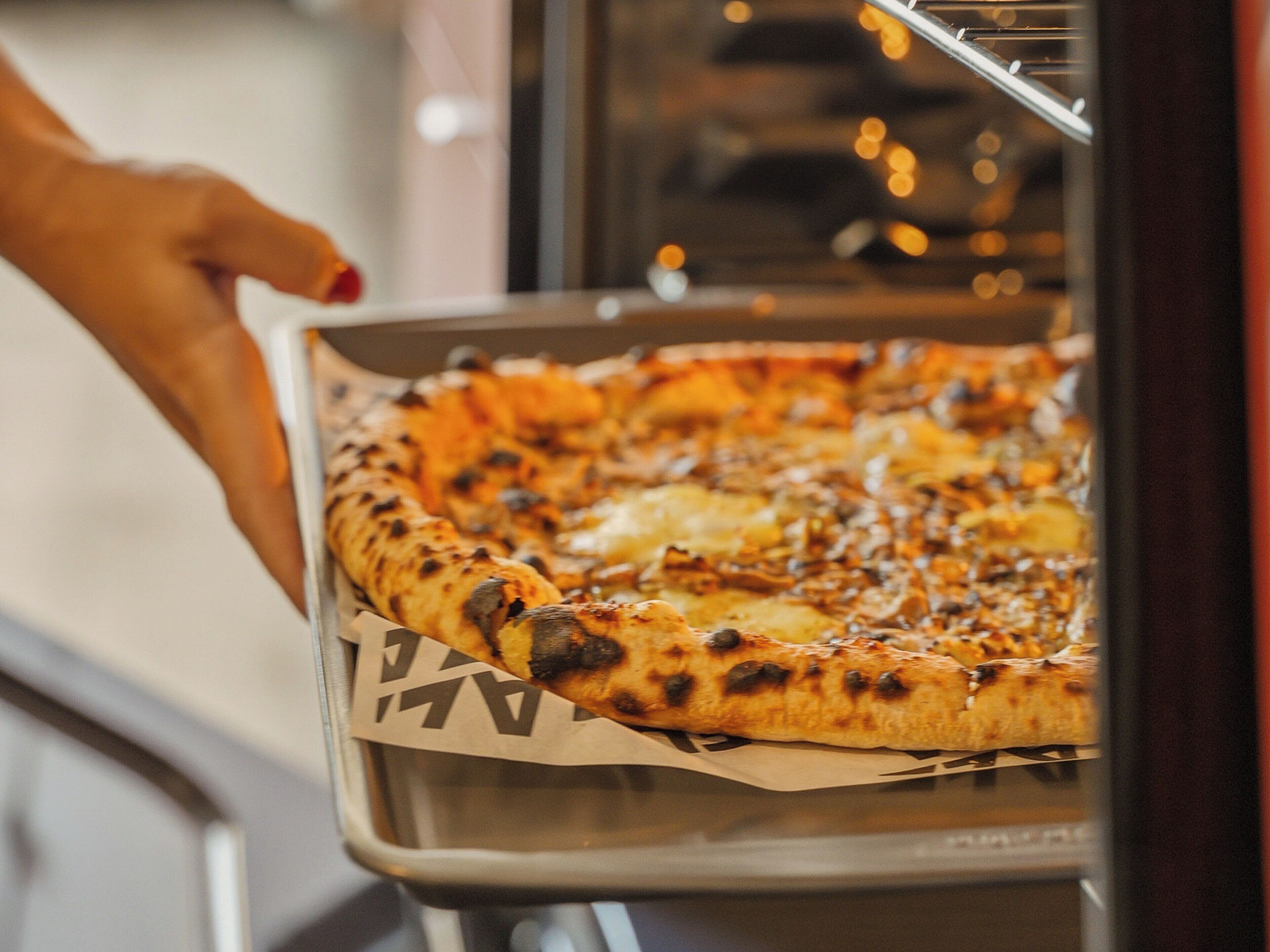 Eine Pizza in einer Metallform im Ofen.
