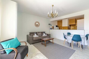 Ein modernes Wohnzimmer mit einer Couch, einem Couchtisch und einem Essbereich mit Stühlen.