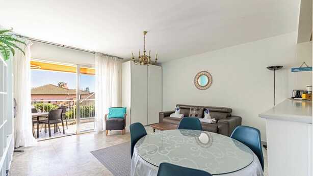 Una sala de estar moderna con un sofá, sillas, una mesa de comedor y una araña.