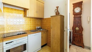 Una cocina con armarios de madera, lavavajillas, estufa y un reloj en la pared.