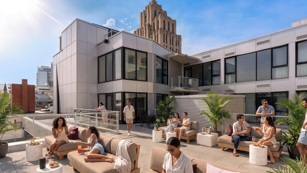 Un salon sur le toit avec des sièges en plein air, un bâtiment moderne en arrière-plan et un ciel dégagé.