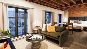 Une chambre d’hôtel moderne avec un plafond en bois, de grandes fenêtres, un canapé, un lit et une table basse.