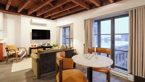 Un salon avec un canapé, des fauteuils, un téléviseur et une table à manger.