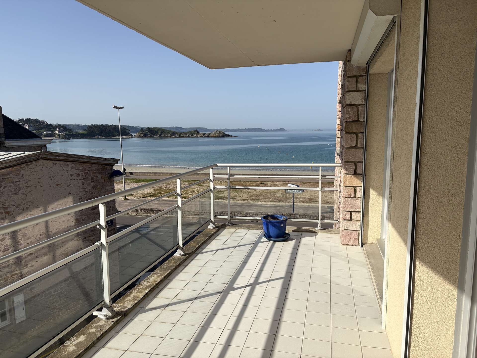 A balcony with a view of the sea, a trash bin, and a street sign.