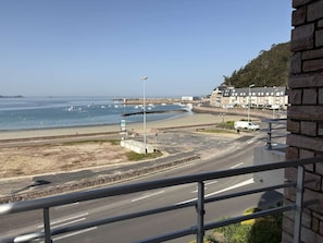 A coastal road with a beach, a lighthouse, and buildings in the background. - Seafront apartment in Erquy | 4 guests | Ref 506 (ERQUY)