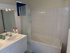 Ein Badezimmer mit zwei Waschbecken, einem Spiegel, einer Duschkabine und einer Badewanne.