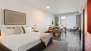 A hotel room with a large bed, a dining table with chairs, a TV, and a window with blinds. - Loft | Appartement paisible Vieux-Montréal, cour intérieure, cuisine équipé (Montréal)