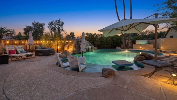 Un jardin avec une piscine, des chaises longues et une cascade décorative.