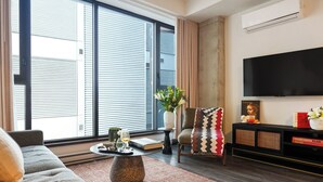 Una sala de estar moderna con un sofá, una mesa de centro, un televisor y una estantería.