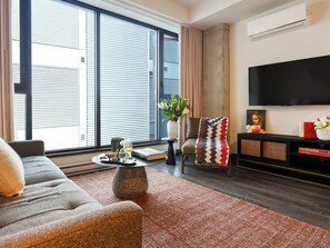 Ein modernes Wohnzimmer mit einer Couch, einem Couchtisch, einem Fernseher und einem Bücherregal.