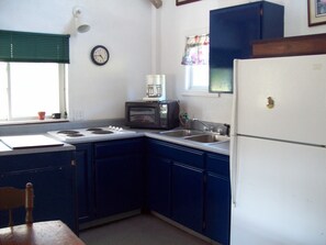 A compact kitchen with a stove, microwave, sink, and refrigerator. - Tranquility surrounds this house. View includes Three Lakes &  Quiet wilderness. (Jeannette)