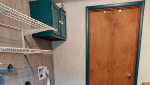 A room with a wooden door, a white radiator, a shelf unit, and a white pipe on the wall. - Tranquility surrounds this house. View includes Three Lakes &  Quiet wilderness. (Jeannette)