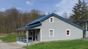 A single-story building with a covered porch, a small window, and a gravel driveway. - Tranquility surrounds this house. View includes Three Lakes &  Quiet wilderness. (Jeannette)