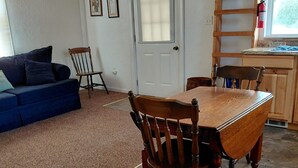 A dining area with a wooden table and chairs, a blue sofa, and a door with a window. - Tranquility surrounds this house. View includes Three Lakes &  Quiet wilderness. (Jeannette)