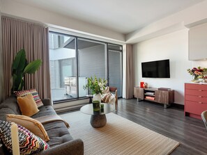 A modern living room with a sofa, coffee table, and a flat-screen TV mounted on the wall. - Loft with Balcony | Boutique Apartment Old Montreal, Courtyard, Full Kitche (Montréal)