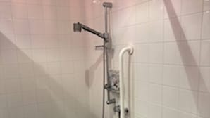 Pieni, laatoitettu kylpyhuone, jossa on suihku, wc ja pesuallas.