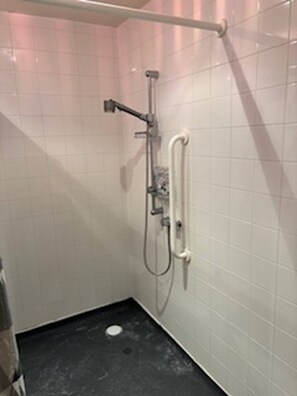 Ein kleines Badezimmer mit gefliesten Wänden, einer Dusche, einer Toilette und einem Waschbecken.