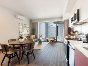 A modern apartment with a dining area, kitchen, and a large sliding glass door leading to a balcony. - Loft with Balcony | Accessible Apartment Old Montreal, Courtyard (Montréal)