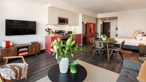 A modern living room with a flat-screen TV, a dining area, a kitchen with a microwave, and a separate bedroom with a bed and a washing machine. - Loft with Balcony | Furnished Apartment Old Montreal, Accessible (Montréal)