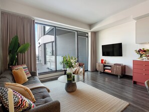 A modern living room with a sofa, coffee table, and a flat-screen TV. - Loft with Balcony | Apartment Old Montreal, River View, Accessible (Montréal)