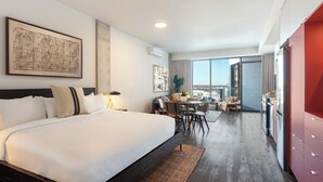Ett modernt hotellrum med en stor säng, en matplats och utsikt över staden.