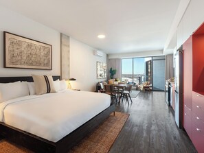 Ein modernes Hotelzimmer mit einem großen Bett, einer Essecke und Blick auf die Stadt.