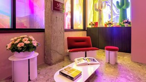 A reception area with a red sofa, a white table with books, a potted plant, and a sign for 'Hôtel Brésil'. - Two-Bedroom Suite | Private Apartment Old Montreal, Quiet Retreat, King Bed (Montréal)