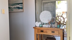 Ein Holzkonsolentisch mit Schubladen, ein großer weißer Ventilator und verschiedene dekorative Gegenstände, darunter ein Schiffsschwengel.