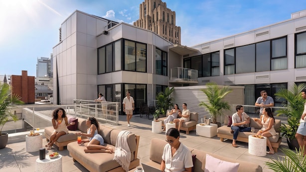 En tagterrasse med udendørs siddepladser, en moderne bygning i baggrunden og en klar himmel.