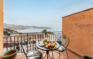 Un balcon avec une table préparée pour le petit-déjeuner, offrant une vue sur la côte.
