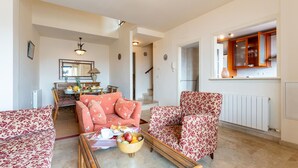 Ein Wohnzimmer mit Sofa, Sessel und Couchtisch mit Obst.