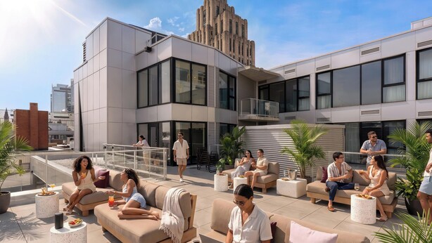Un lounge en la azotea con mesas al aire libre, un edificio moderno al fondo y un cielo despejado.