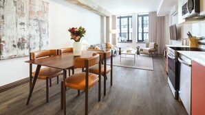 Una sala de estar moderna con comedor, cocina y ventanas amplias.