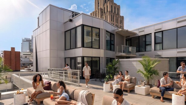 Un salon sur le toit avec des sièges en plein air, un bâtiment moderne en arrière-plan et un ciel dégagé.