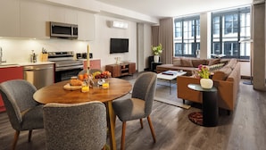 A modern living room with a dining area, kitchen, and large windows. - One-Bedroom Suite | Bright Apartment Old Montreal, Street View, Open Living (Montréal)