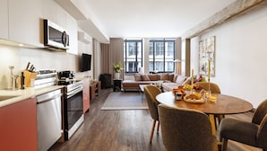 A modern kitchen with a dining area, a sofa, and a TV. - One-Bedroom Suite | Bright Apartment Old Montreal, Street View, Open Living (Montréal)