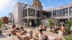 Een dakterras met buitenmeubilair, op de achtergrond een modern gebouw en een heldere lucht.