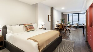 Habitación de hotel con una cama grande, un escritorio y vistas a la ciudad.