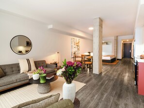 Een moderne woonkamer met een bank, salontafel en een eethoek met stoelen.