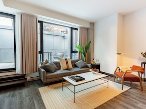 A modern living room with a sofa, coffee table, and a view of the outside. - Loft with Terrace | Bright Apartment Old Montreal, Street View (Montréal)