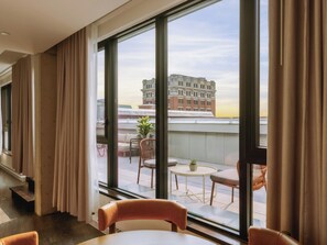 A hotel room with large windows, a view of the cityscape, a balcony with outdoor furniture, and a modern interior design. - One-Bedroom Suite with Terrace|Luxury Apartment Old Montreal, Bright Space (Montréal)